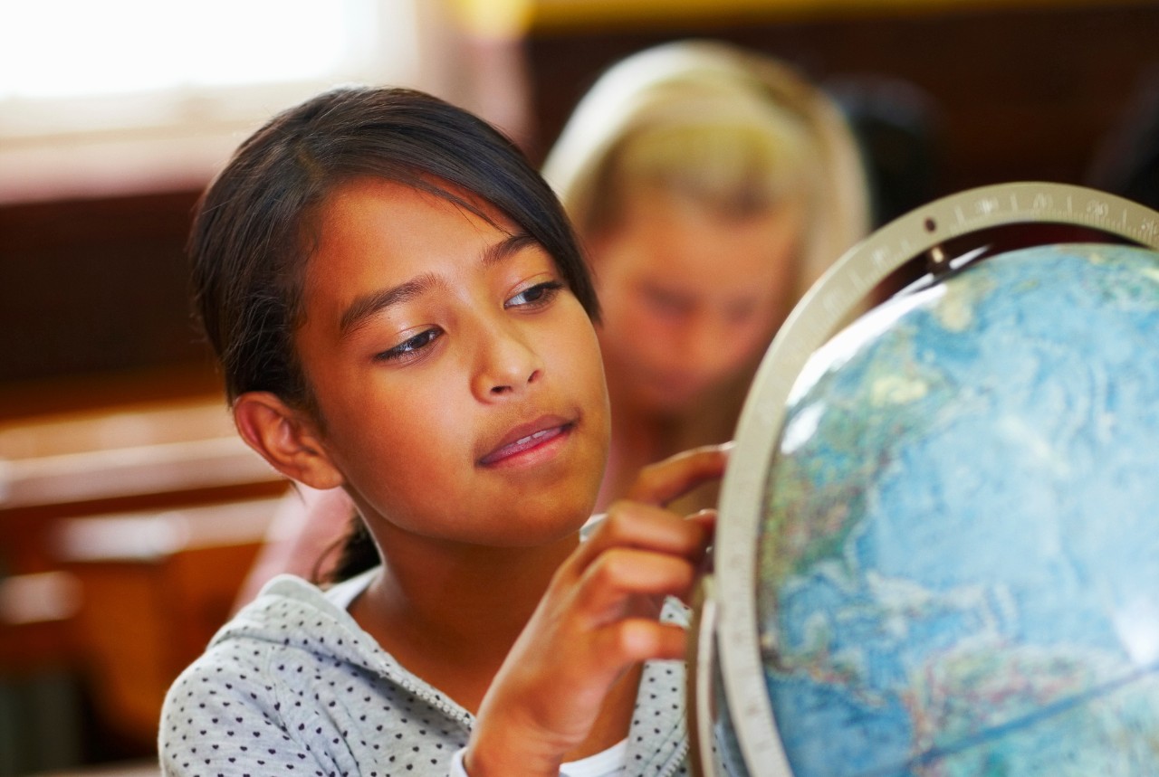 Young Asian schoolgirl studying the world globe at school